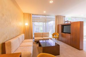 a living room with a couch and a tv at NEW Rixwell Collection Seaside Hotel Jurmala in Jūrmala