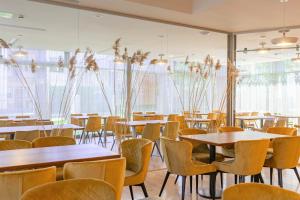 um restaurante com mesas, cadeiras e janelas em NEW Rixwell Collection Seaside Hotel Jurmala em Jūrmala