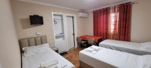a hotel room with two beds and a desk at AAA Apartment in Berat