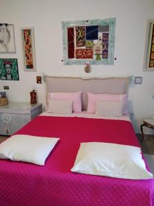 a bedroom with a large bed with a pink blanket at Stanza privata casa artistica Mariola in San Sperate
