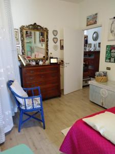a bedroom with a dresser and a chair and a mirror at Stanza privata casa artistica Mariola in San Sperate