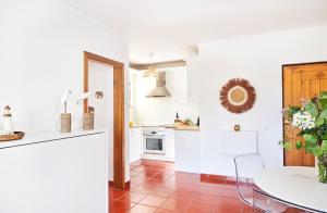 a kitchen with white walls and a red tile floor at Troia beach Vacation in Troia