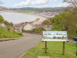 a sign in the grass next to a road at Pebblestone Cottage in Llandudno