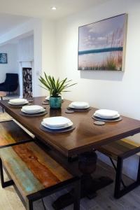 a wooden dining room table with plates on it at Woodnesborough Cottages in Eastry