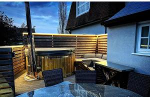 a deck with a hot tub and a table and chairs at Woodnesborough Cottages in Eastry