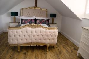 a bedroom with a king sized bed with golditures at Woodnesborough Cottages in Eastry