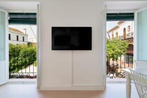 uma sala de estar com televisão numa parede branca em Orange Square Rooftop Apartment 250 m2 em Marbella