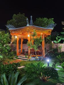 a gazebo in a garden at night at Mộc House (Green House) 