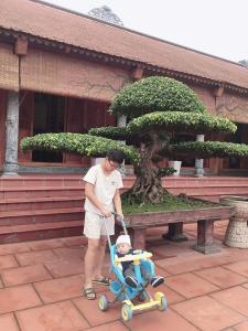 mężczyzna pchający dziecko w wózku w obiekcie Mộc House (Green House) 