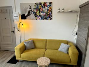 a yellow couch in a living room with a painting at Bienvenue au Quai 27 in Épernay