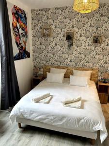 Un dormitorio con una cama blanca con un cuadro en la pared. en Bienvenue au Quai 27, en Épernay