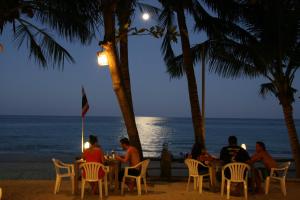 people sitting at a table on the beach at night at Palita Lodge - SHA Plus in Haad Rin