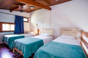 een slaapkamer met 2 bedden met blauwe en witte lakens bij Pousada Azul Banana - Maresias in Maresias