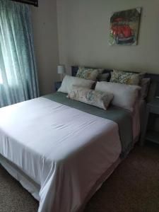 una camera da letto con un grande letto con lenzuola e cuscini bianchi di Nzima BnB a Estcourt