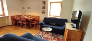 Una sala de estar con un sofá, una mesa y un televisor. en Ai Grisi, en Cavalese