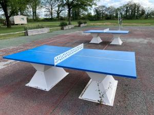dos mesas de ping pong sentadas en un estacionamiento en Mobile home 3 chambres Camping Cœur de Vendée 3 étoiles, en La Boissière-de-Montaigu