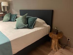 Un dormitorio con una cama con almohadas verdes y una mesa. en Maison Margareta en Middelburg