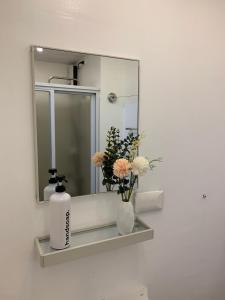 een badkamer met een spiegel en een vaas met bloemen op een plank bij Casa Lim SMDC Light Residences Tower 3 in Manilla