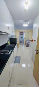 a kitchen with white cabinets and a living room at Casa Lim SMDC Light Residences Tower 3 in Manila