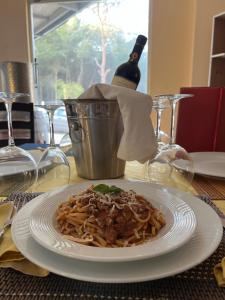 a plate of pasta on a table with a bottle of wine at Hotel Garden Albania in Golem