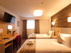 a hotel room with two beds and a desk at Caledonian Hotel 'A Bespoke Hotel’ in Ullapool