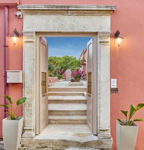 una puerta abierta a un edificio rosa con escaleras en Arhontiko Arhanes Suites, en Archanes