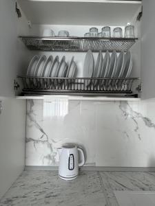 uma chávena de café branca sentada numa prateleira na cozinha em Квартира по вул. Огієнка 2а em Lutsʼk