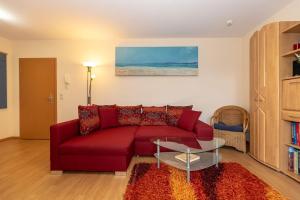 a living room with a red couch and a glass table at Yachthafenresidenz-Wohnung-8112-850 in Kühlungsborn