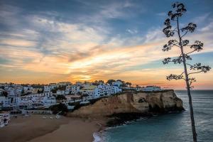 Blick auf einen Strand mit weißen Gebäuden auf einer Klippe in der Unterkunft Colors Pool House in Carvoeiro