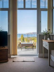 a room with a large window with a view of a balcony at Cae Glas in Penmaen-mawr