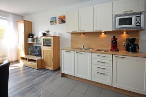 eine Küche mit weißen Schränken und einer Arbeitsplatte in der Unterkunft Yachthafenresidenz - Wohnung 9103 / 879 in Kühlungsborn