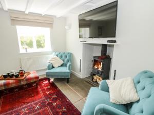 salon z 2 niebieskimi krzesłami i kominkiem w obiekcie Nash Cottage w mieście Leominster