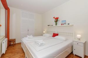 キュールングスボルンにあるResidenz-Seestern-Wohnung-7-931の白を基調としたベッドルーム(赤をアクセントにした大きな白いベッド1台付)