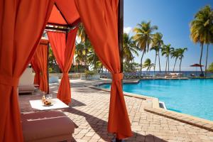 Carambola Beach Resort St. Croix, US Virgin Islands في North Star: مسبح بمظلات برتقال وطاولة بجانب الماء