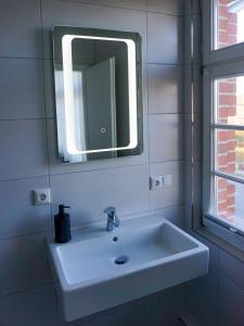 ein weißes Waschbecken im Bad mit Spiegel in der Unterkunft Ferienwohnungen Molli-West - Wohnung 2 / 9802 in Kühlungsborn