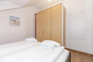 キュールングスボルンにあるAm-Stadtwald-Wohnung-23-9790の白いベッド2台と木製キャビネット付きのベッドルーム1室が備わります。