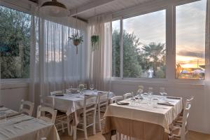 ein Esszimmer mit weißen Tischen und großen Fenstern in der Unterkunft Hotel Reverse in Torre Santa Sabina