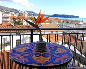 a table with a flower in a vase on a balcony at Hotel TEA - Praia a Mare in Praia a Mare