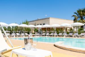 ein Tisch mit Brille neben einem Pool in der Unterkunft Hotel Reverse in Torre Santa Sabina