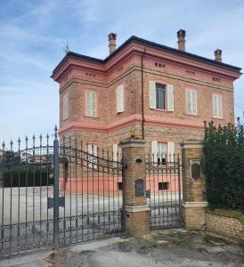 ein altes Backsteinhaus mit einem Zaun davor in der Unterkunft Villa Livia in Fermo