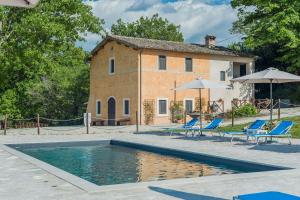 a house with a swimming pool in front of a building at Casale Andrea in Spoleto