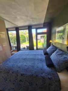 a bedroom with a large blue bed with windows at Bed & Breakfast 28 Appartement met Privé Tuin in Assen