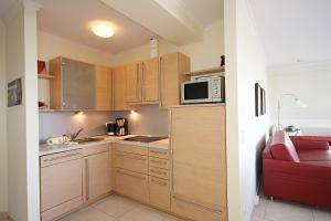 キュールングスボルンにあるHaus-Miramare-Wohnung-33-315の小さなキッチン(木製キャビネット、赤いソファ付)