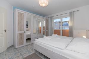 キュールングスボルンにあるAm-Yachthafen-Villa-Fehmarn-Wohnung-38-586の白いベッドルーム(大型ベッド1台、窓付)