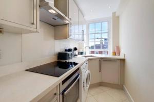 - une cuisine blanche avec évier et cuisinière dans l'établissement MODERN 2 BED 2 BATH CLOSE TO OXFORD STREET, à Londres