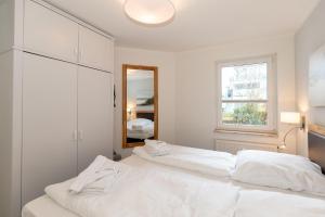 キュールングスボルンにあるYachthafenresidenz-Wohnung-5104-808の白いベッドルーム(ベッド2台、鏡付)