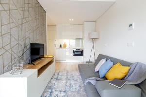 a living room with a gray couch and a kitchen at Dragão - Indigo Antas Park in Porto