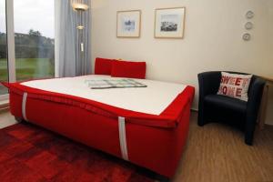 a red bed and a chair in a room at Yachthafenresidenz-Wohnung-9107-829 in Kühlungsborn