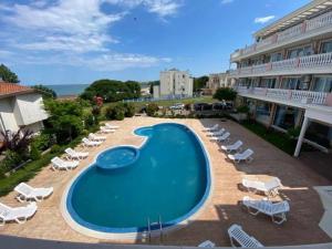 une piscine avec des chaises longues et un hôtel dans l'établissement Студио Симона 5 първа линия море, à Lozenets