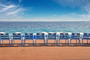 a row of blue chairs sitting on the beach at Central Rossini Flat with Balcony in Nice